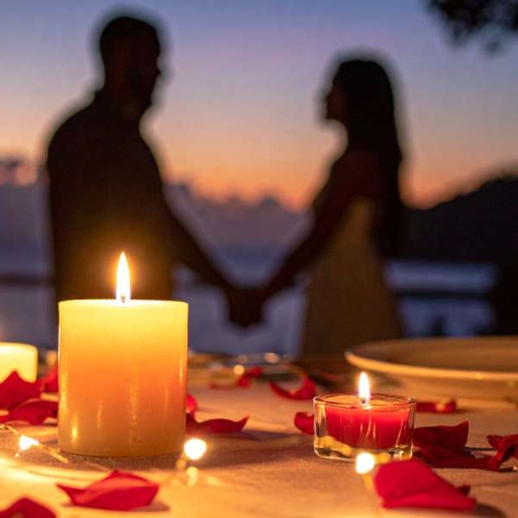 Romantic couple watching sunset at Ella Rock overlooking misty mountains in Sri Lanka
