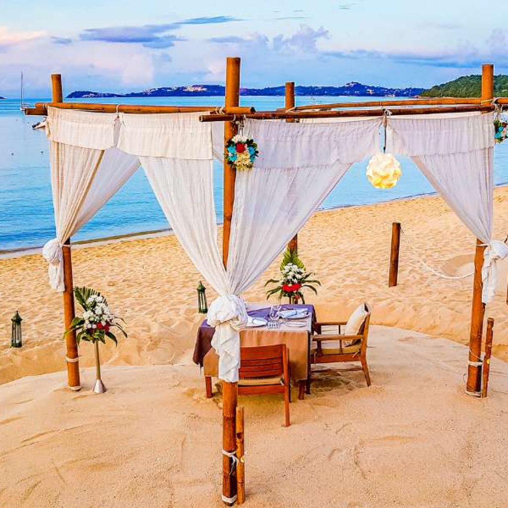 Honeymooners enjoying private candlelit dinner on Mirissa beach at sunset