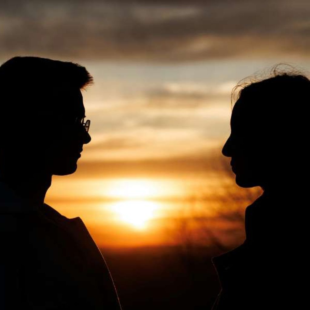 Romantic couple watching sunset at Ella Rock overlooking misty mountains in Sri Lanka