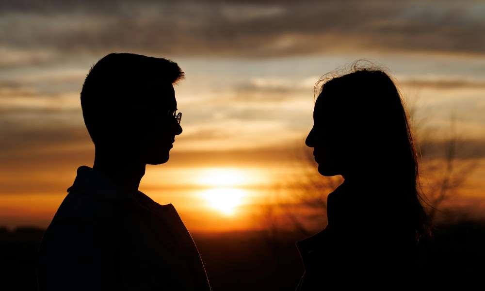 Romantic couple watching sunset at Ella Rock overlooking misty mountains in Sri Lanka
